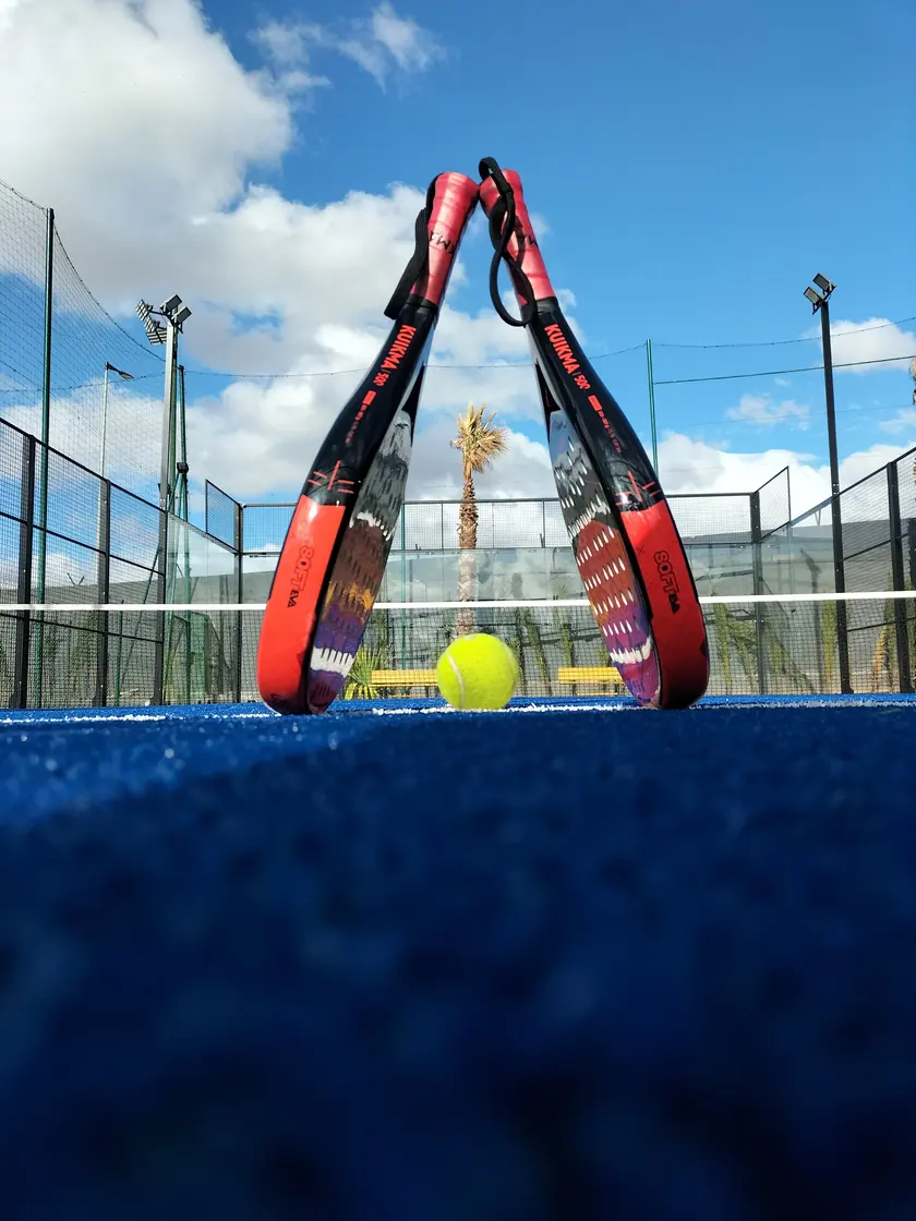 Raquettes et balle sur le terrain de padel.